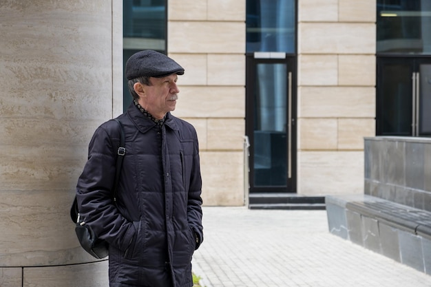 Un homme de race blanche adulte se tient près d'un bâtiment moderne avec des colonnes