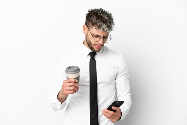 Homme de race blanche d'affaires isolé sur fond blanc tenant du café à emporter et un mobile
