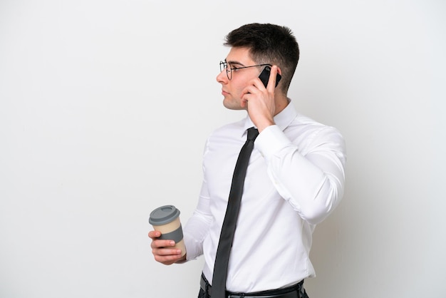 Homme de race blanche d'affaires isolé sur fond blanc tenant du café à emporter et un mobile