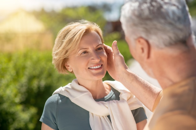 Homme de race blanche aux cheveux gris caressant le visage de sa belle femme blonde heureuse souriante d'âge moyen