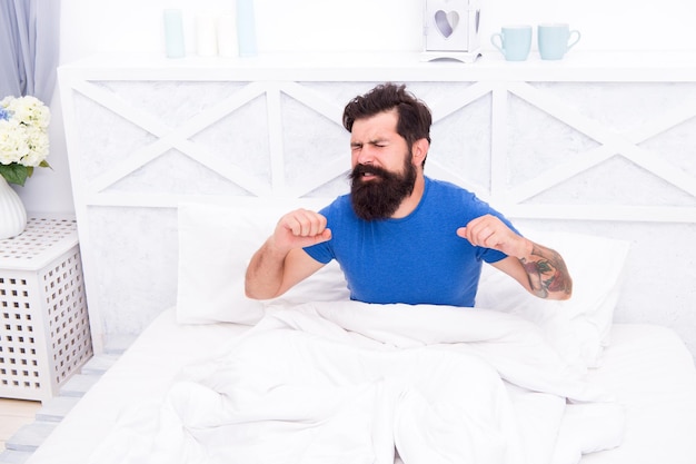 Homme de race blanche avec barbe allongé sur le lit après avoir dormi dans une pièce lumineuse matin qui s'étend