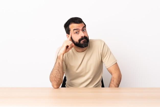 Homme de race blanche avec barbe dans une table en pensant à une idée.