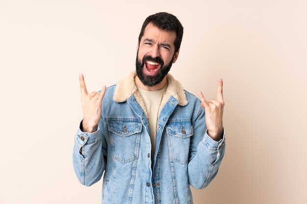 Homme de race blanche avec barbe sur fond isolé faisant le geste de la corne