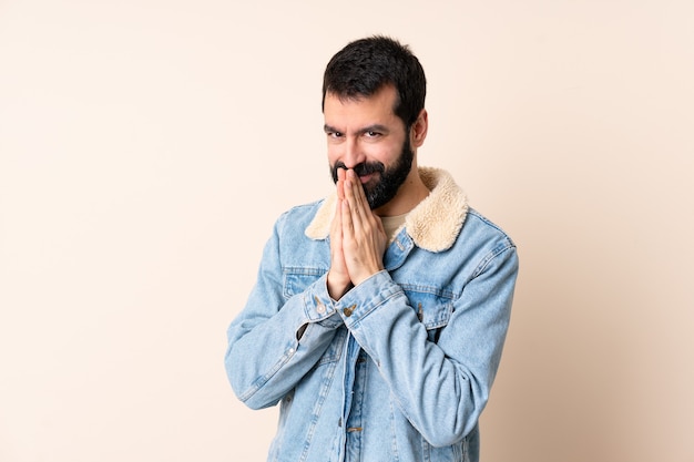 Homme de race blanche avec barbe sur fond isolé maintient la paume ensemble. La personne demande quelque chose