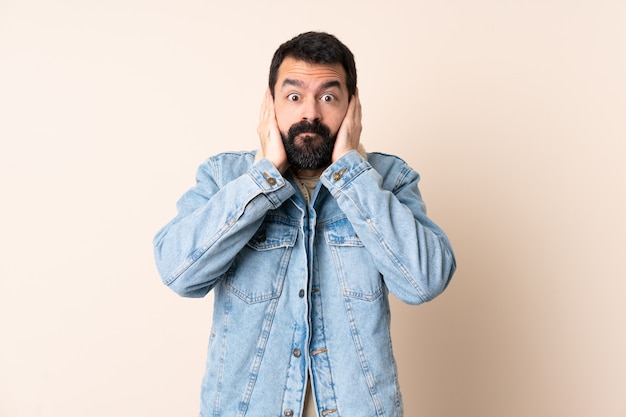 Homme de race blanche avec barbe sur mur frustré et couvrant les oreilles