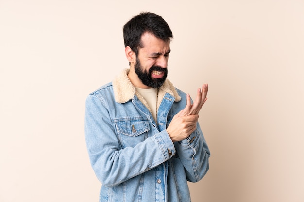 Homme de race blanche avec barbe sur mur souffrant de douleurs dans les mains