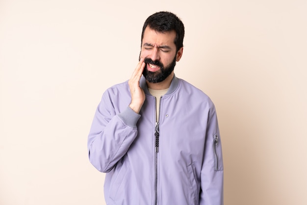 Homme de race blanche avec barbe portant une veste sur le mur avec des maux de dents