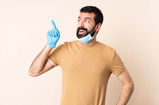 Homme de race blanche avec barbe protégeant avec un masque et des gants sur le mur dans l'intention de réaliser la solution tout en levant un doigt