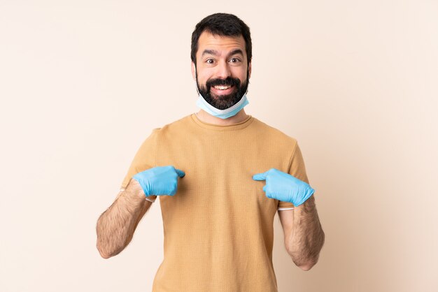 Homme de race blanche avec barbe protégeant avec un masque et des gants sur le mur avec une expression faciale surprise