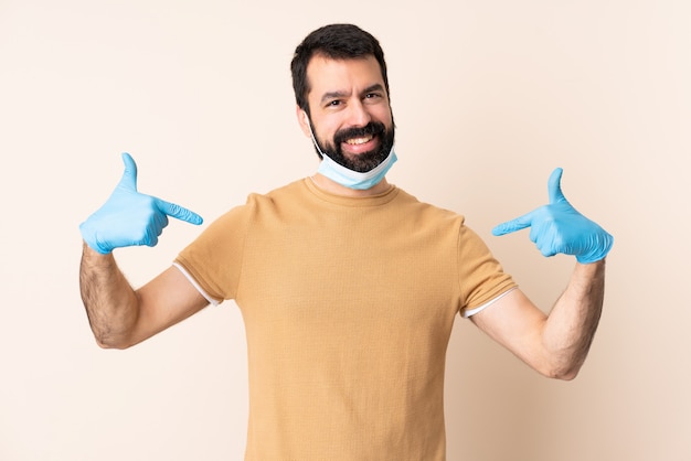 Homme de race blanche avec barbe protégeant avec un masque et des gants sur un mur isolé fier et satisfait de lui-même
