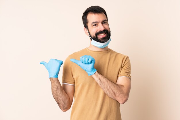 Homme de race blanche avec barbe protégeant avec un masque et des gants sur le mur pointant vers le côté