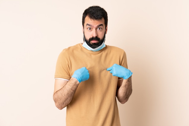 Homme de race blanche avec barbe protégeant avec un masque et des gants sur le mur pointant vers soi