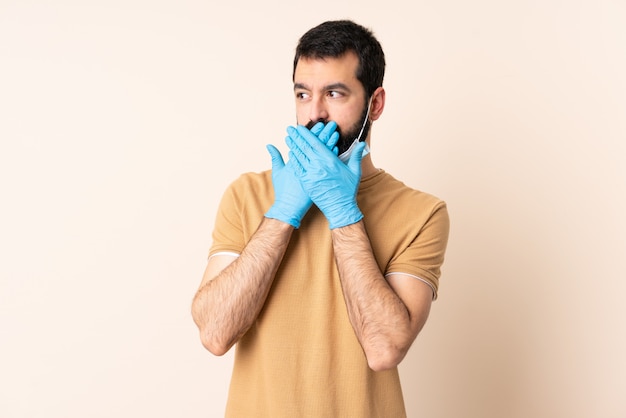 Homme de race blanche avec barbe protégeant avec un masque et des gants sur le revêtement mural bouche avec les mains
