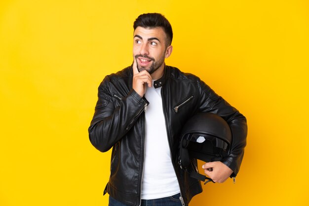 Homme de race blanche avec un casque de moto sur jaune en pensant à une idée