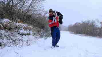 Photo homme de race blanche avec un chien border collie dans ses bras dans la neige