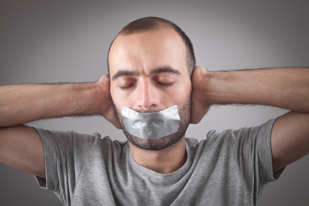 Homme de race blanche avec du ruban adhésif sur la bouche. La censure