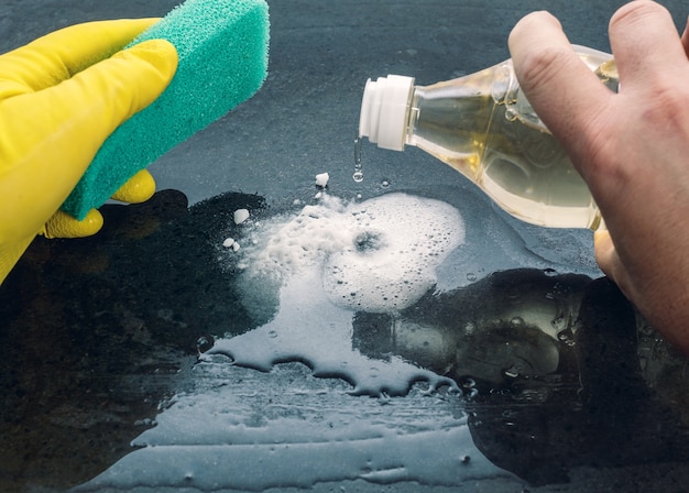 Un Homme De Race Blanche, Avec Une éponge Verte à La Main Et Des Gants Jaunes, Ajoute Du Vinaigre Au Bicarbonate De Soude Pour Nettoyer Une Surface.