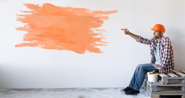 Photo un homme de race blanche est assis sur les planches avec son index pointe vers une tache orange sur le mur baner copy space