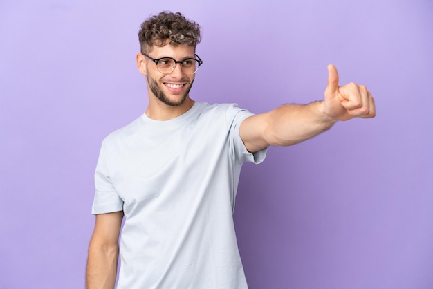 Homme de race blanche de livraison isolé sur fond violet donnant un geste du pouce vers le haut