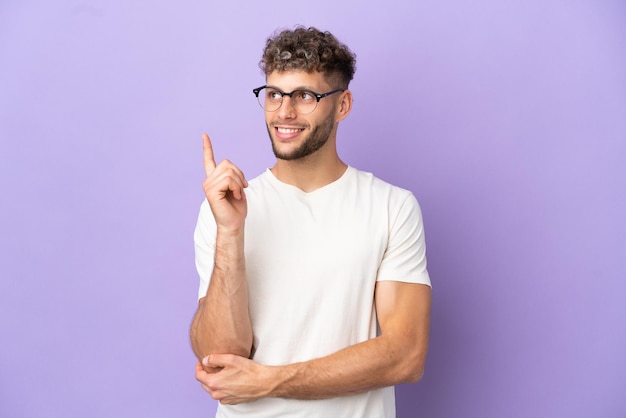 Homme de race blanche de livraison isolé sur fond violet pointant vers une excellente idée