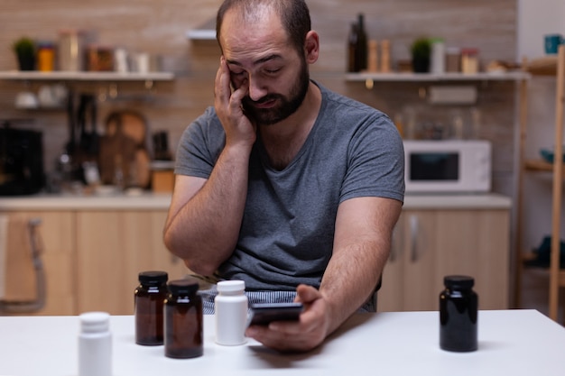 Homme de race blanche avec des maux de tête en regardant un smartphone