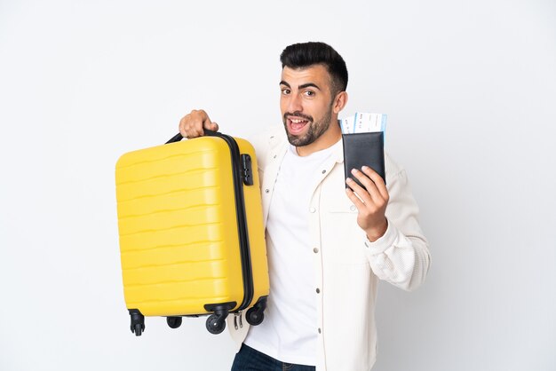 Homme de race blanche sur mur blanc isolé en vacances avec valise et passeport