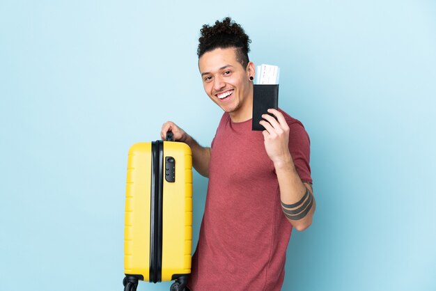 Homme de race blanche sur mur bleu isolé en vacances avec valise et passeport