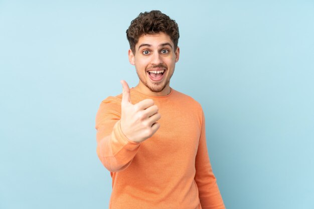 Homme de race blanche sur le mur bleu avec les pouces vers le haut parce que quelque chose de bien s'est produit