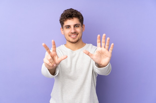 Homme de race blanche sur mur violet comptant huit avec les doigts