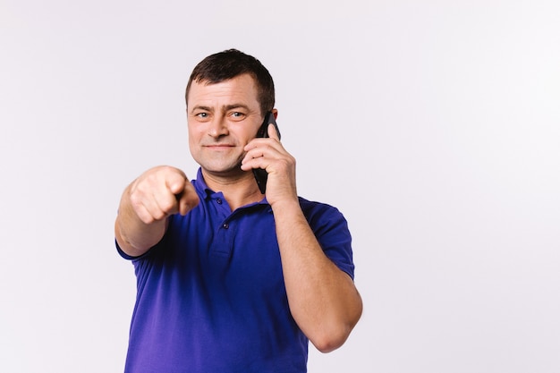 Homme De Race Blanche Parlant Sur Un Téléphone Portable Et Montre Son Index à La Caméra. Fond Blanc Et