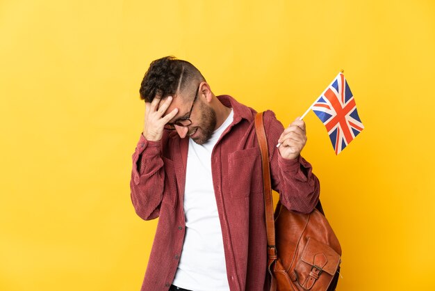 Homme de race blanche tenant un drapeau du Royaume-Uni isolé sur fond jaune en riant
