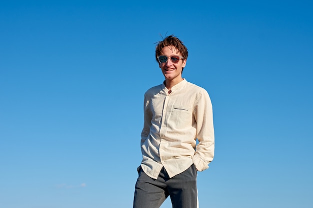 Un homme de race blanche vêtu d'une chemise beige de l'Espagne debout avec les mains dans ses poches sur le ciel