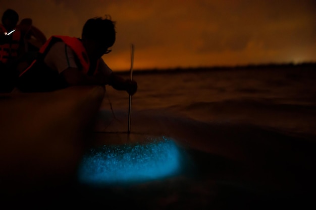 Photo un homme ramant un bateau contre le ciel au coucher du soleil