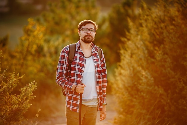 Homme en randonnée dans les montagnes au coucher du soleil avec sac à dos