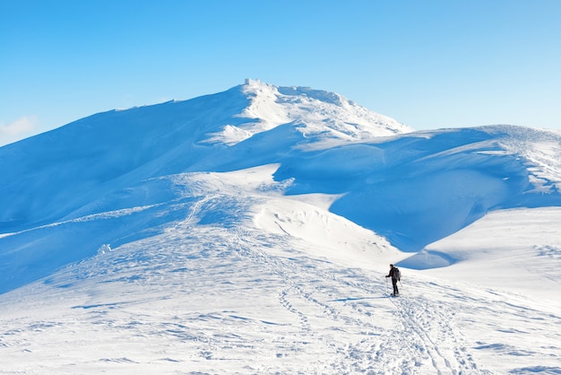 Un homme en randonnée dans les montagnes d'hiver avec de la neige blanche sur les sommets