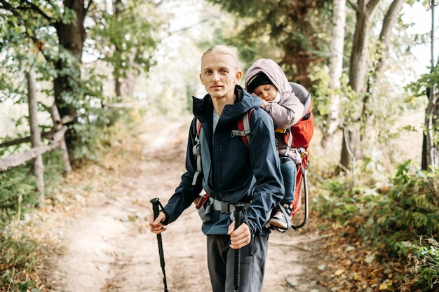 Homme de randonnée avec enfant endormi endormi dans un sac à dos en montagne