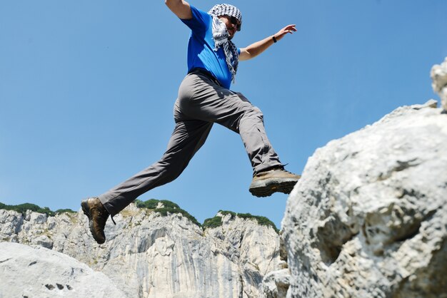 Homme de randonnée qui saute sur les montagnes pour réussir