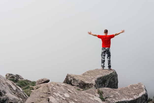 L'homme de randonneur sur le dessus de la montagne apprécie la vue aérienne soulevant ses mains au-dessus des nuages Mont Pidan