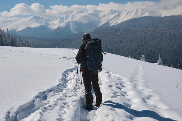 Homme randonneur randonnée à flanc de montagne enneigée par une froide journée d'hiver.