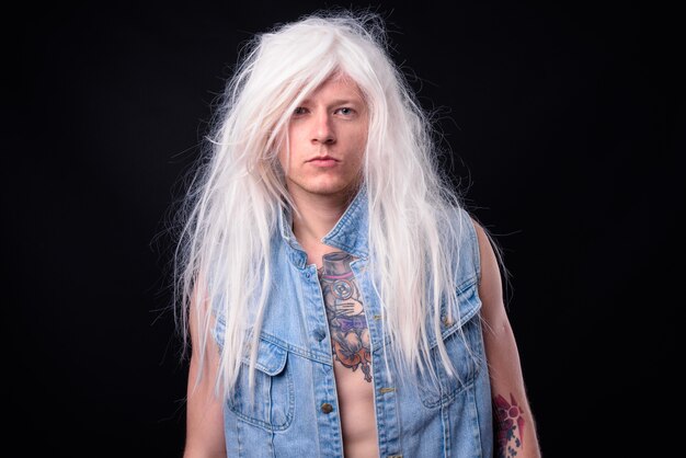 Homme rebelle comme punk rocker portant une perruque torse nu contre noir