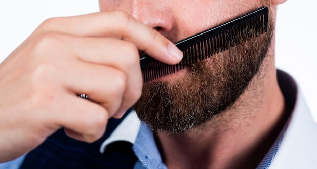 Homme recadré peigner sa barbe avec une brosse à cheveux barbier