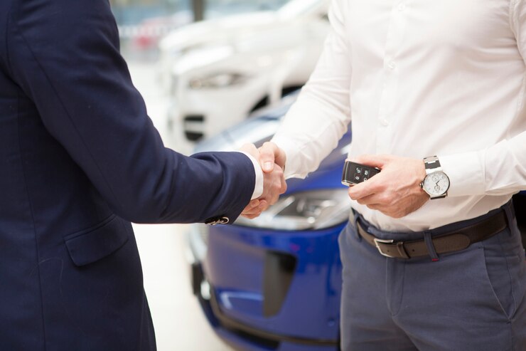 Homme recevant les clés de voiture du vendeur chez le concessionnaire