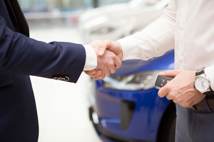 Homme recevant les clés de voiture du vendeur chez le concessionnaire