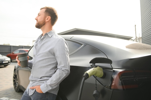 Un homme recharge sa voiture électrique moderne Le concept d'énergie verte