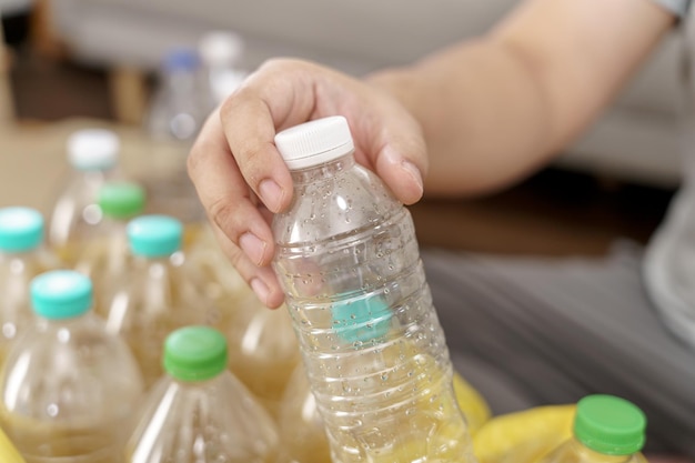 Homme recycle eco vert concept zéro homme jetant une bouteille en plastique vide dans la poubelle de recyclage avec des sacs à ordures jaunes à la maison