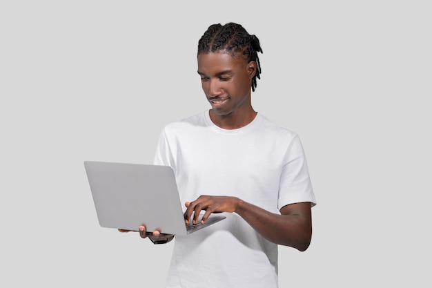 Un homme regardant attentivement l'écran d'un ordinateur portable sur un fond blanc