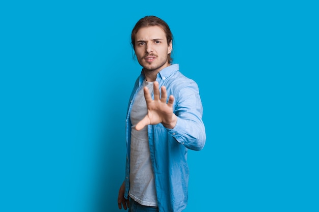 Homme Regardant La Caméra Et Faisant Des Gestes Comme S'il Voulait Arrêter Quelque Chose En Posant Sur Un Mur Bleu