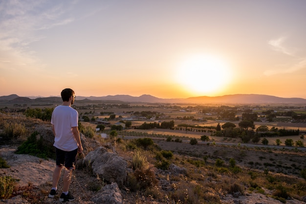 Homme regardant le coucher de soleil dans une montagne