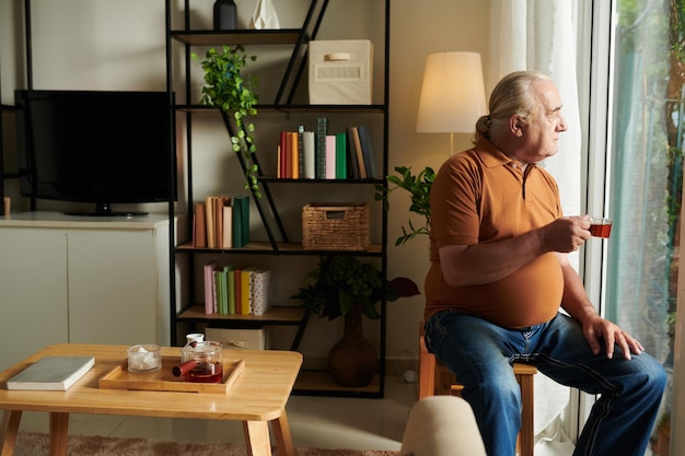 Homme regardant dehors par la fenêtre