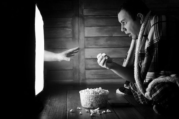 Un homme regardant un film d'horreur à la télévision en noir et blanc